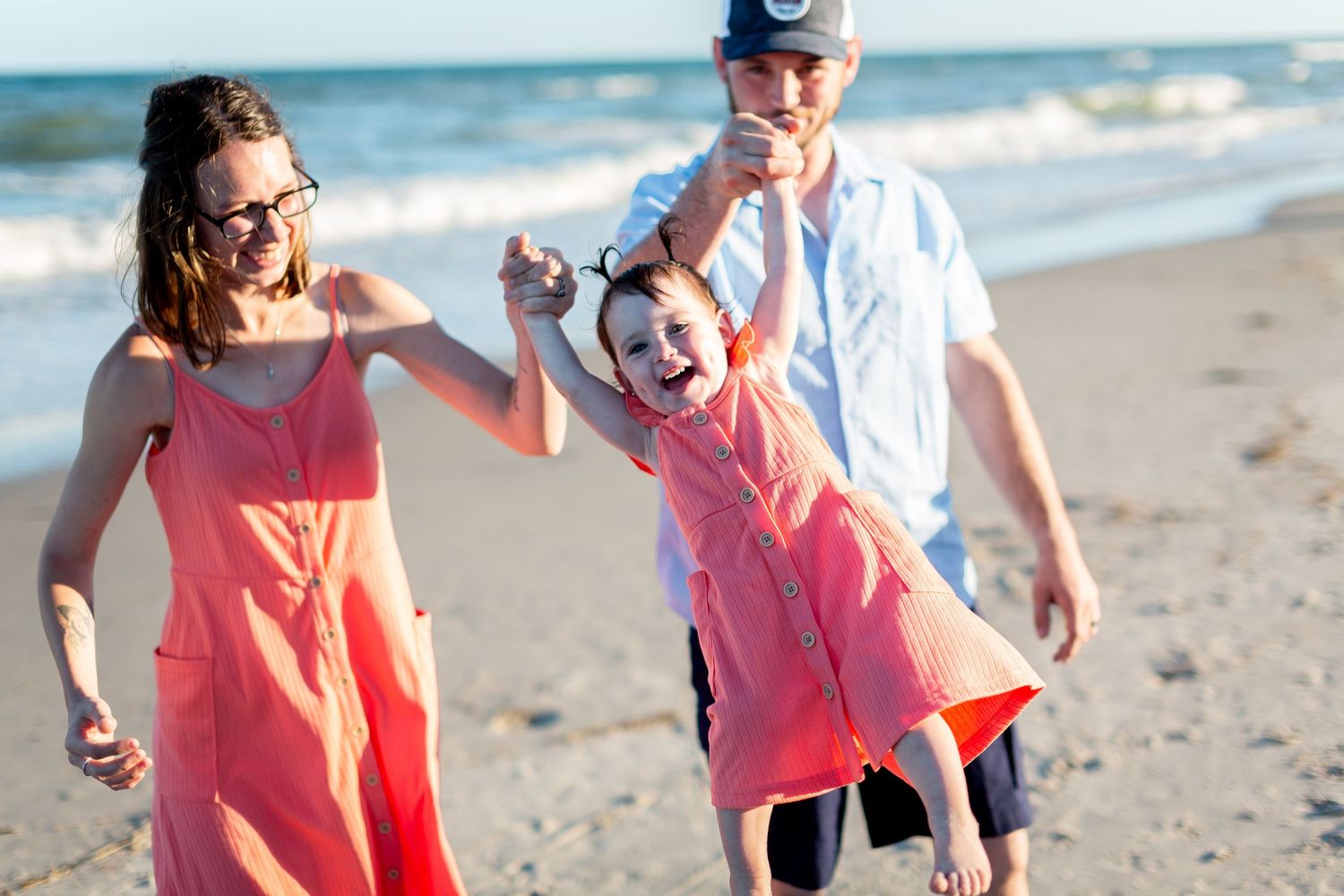 Family walking together along a sunny beach shoreline.