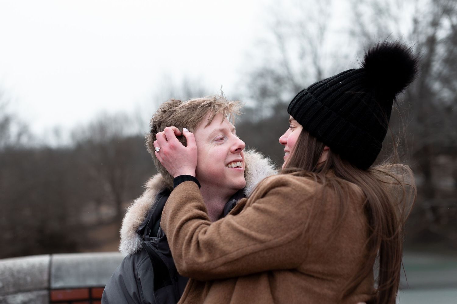Two people share an intimate moment outdoors in winter wearing warm coats and casual attire.