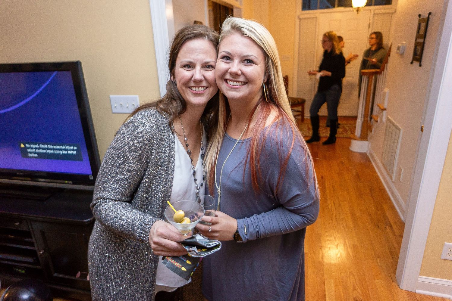 Two people standing close together and smiling at a casual indoor gathering.