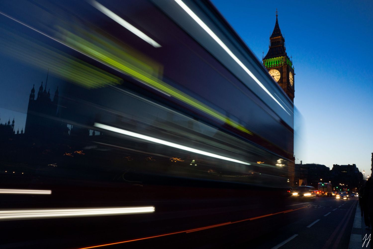 Long exposure shot of double-decker bus passing Big Ben at blue hour in London.
