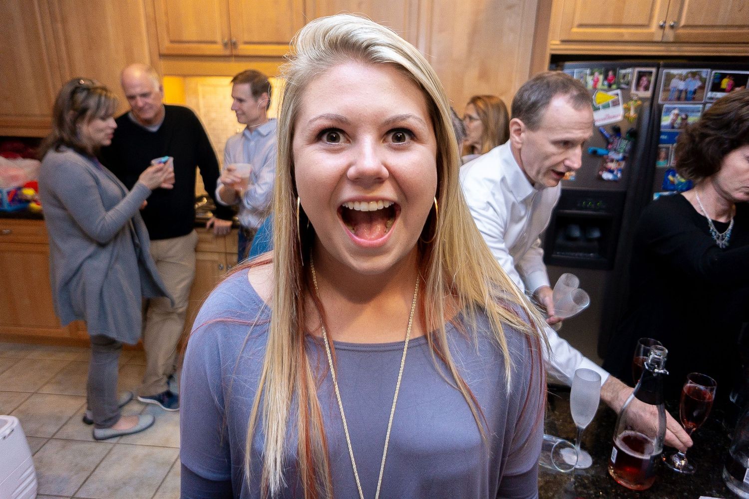 A group of people laughing and socializing at an indoor gathering or party.
