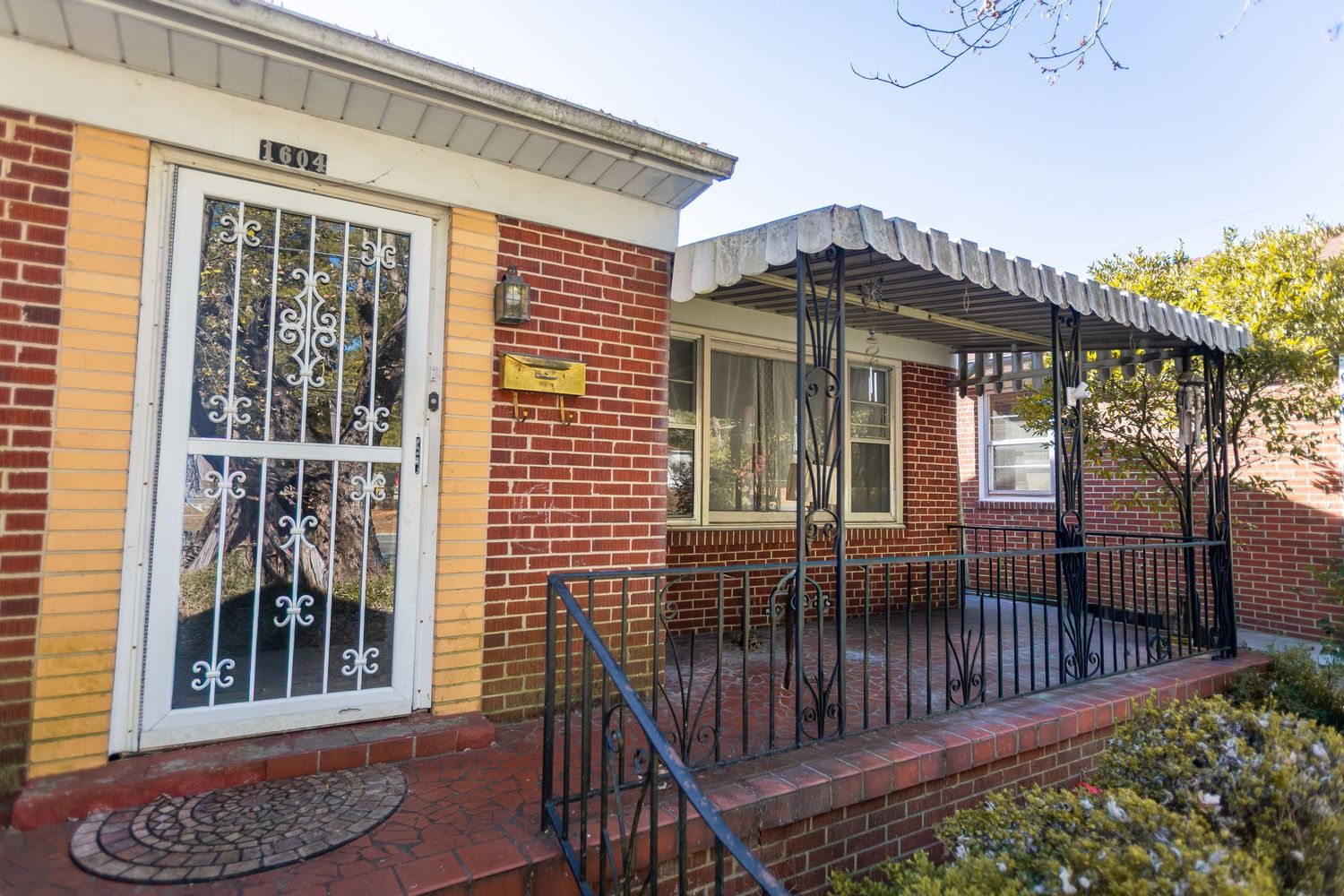 Historic brick building facade with iron railings and white trim details along a walkway.