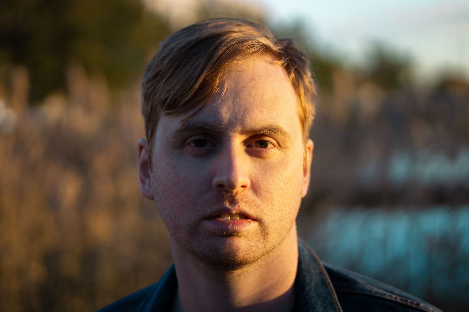 Portrait of young blonde man with stubble in golden hour natural outdoor lighting.