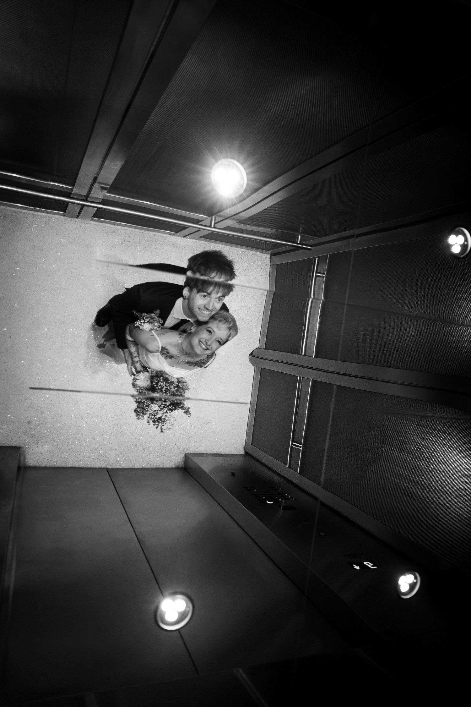 Black and white artistic photo of a graffiti mural on a ceiling with spotlights creating dramatic lighting effects.