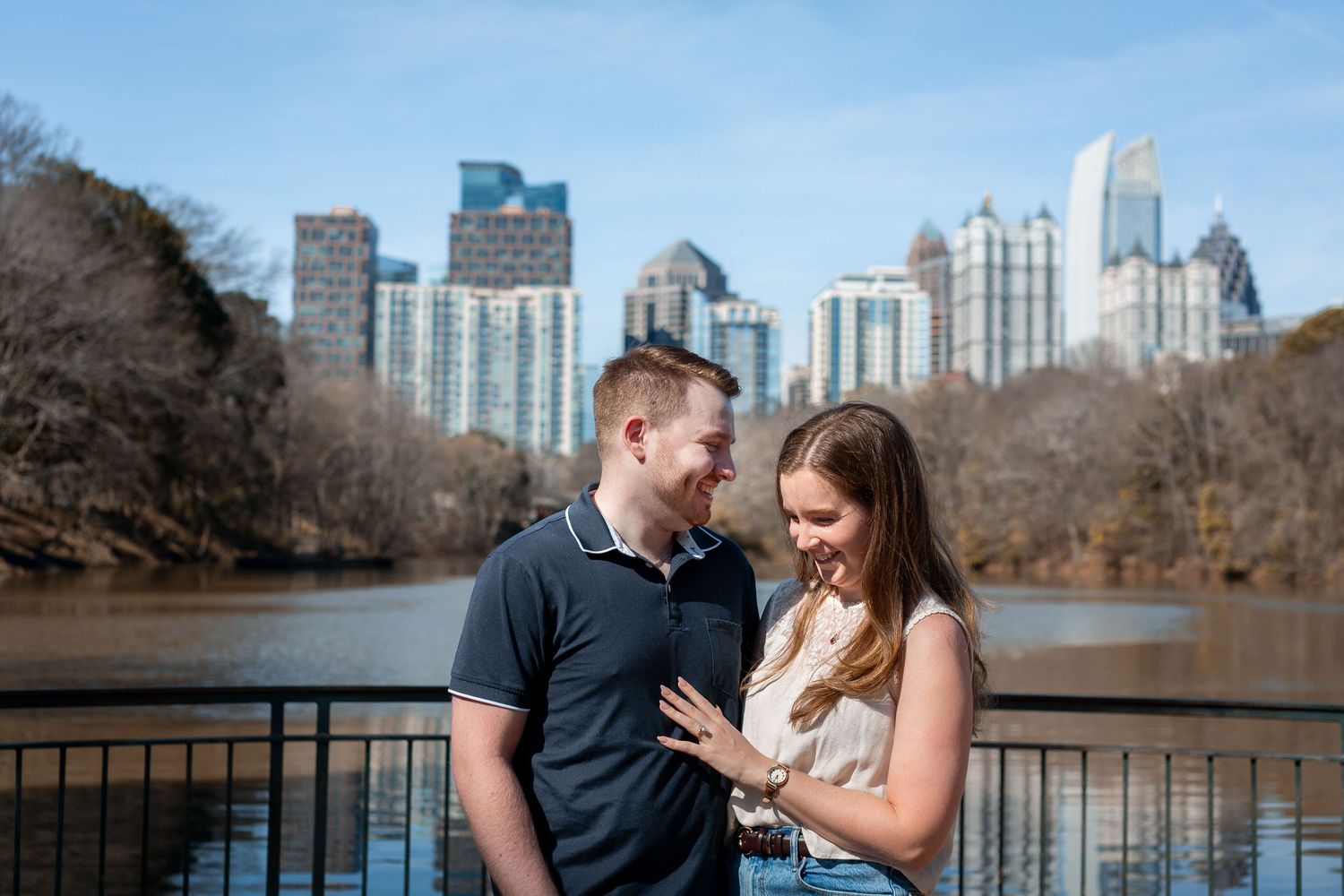 Romantic couple engagement photo session at Atlanta's Piedmont Park with city skyline views in the background.