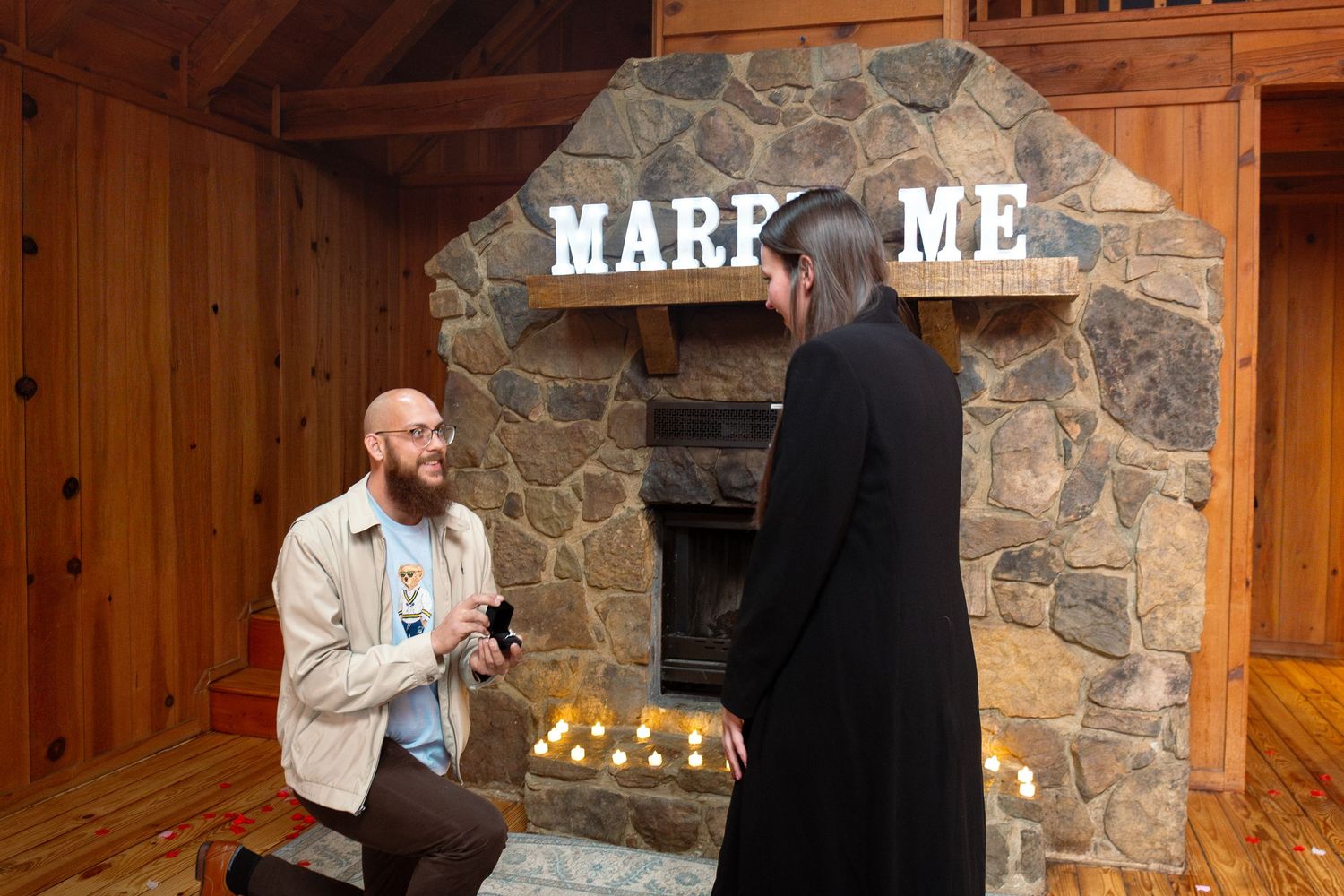 A speaker gestures while giving a presentation in a rustic wood and stone venue with warm lighting.