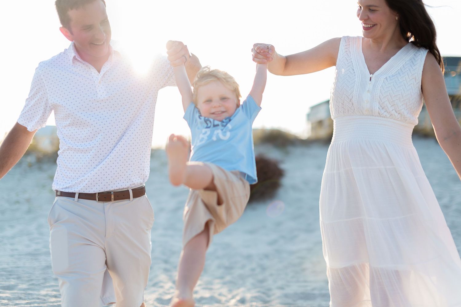 Family dressed in white walks along beach during sunset photoshoot.