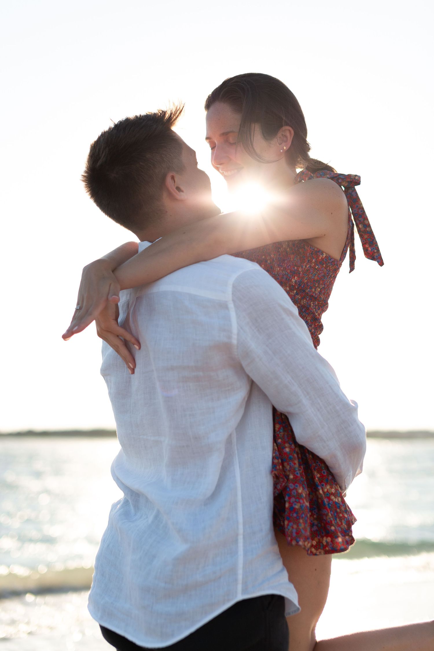 A romantic sunset embrace with backlighting creating a warm glow around the couple.