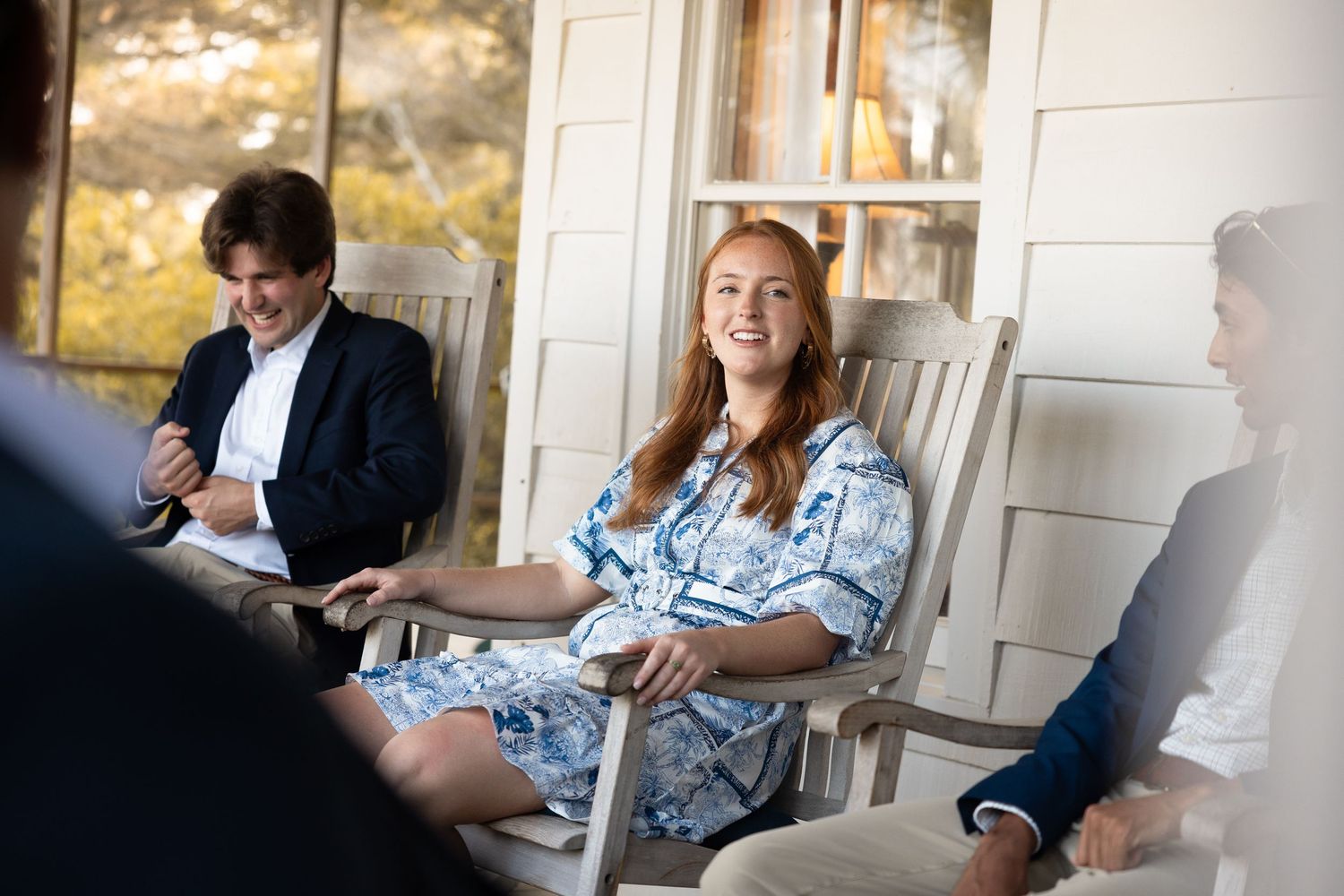 People gathered on a porch having a social conversation outdoors.