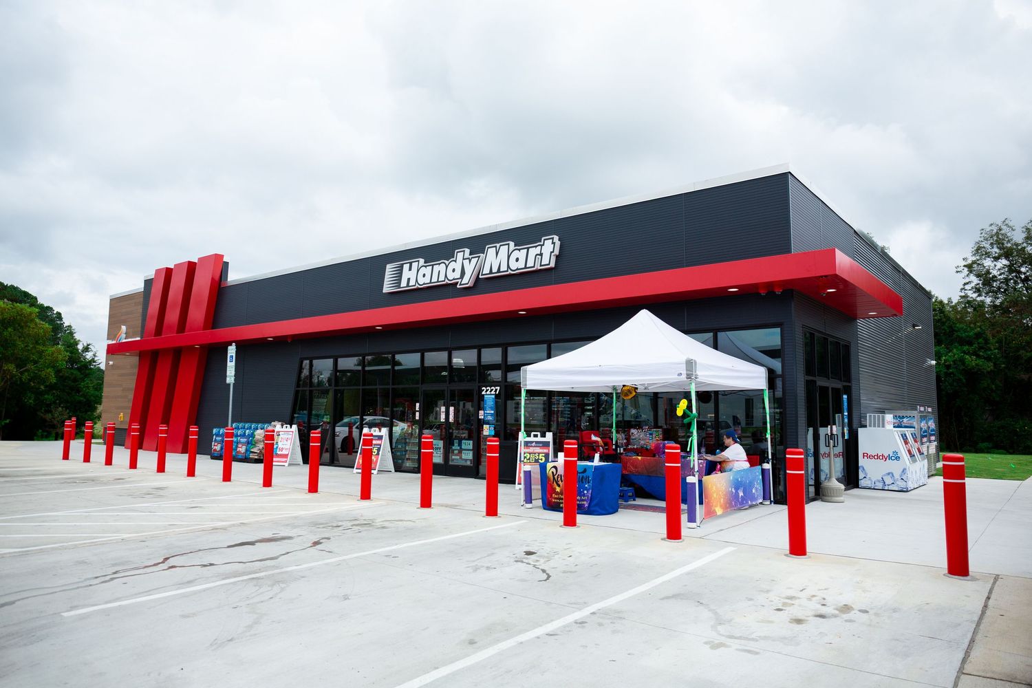Strip mall exterior with red accents and multiple retail storefronts in a shopping center.