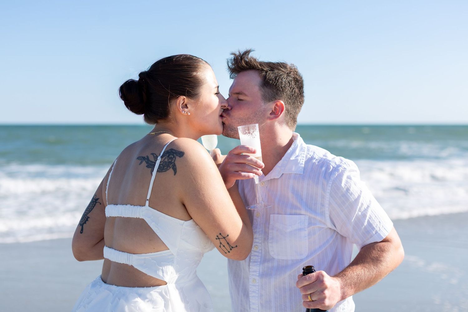 Romantic beach photoshoot with couple embracing on sandy shore near ocean waves.