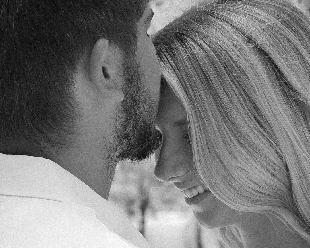 A close black and white photo of a couple nearly kissing during a romantic engagement session.