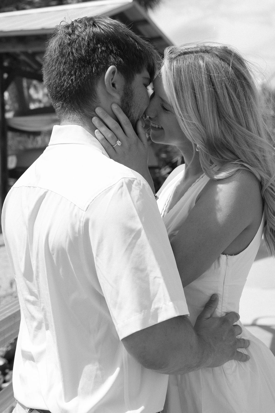 Black and white close-up of a couple about to kiss, woman wearing an engagement ring.