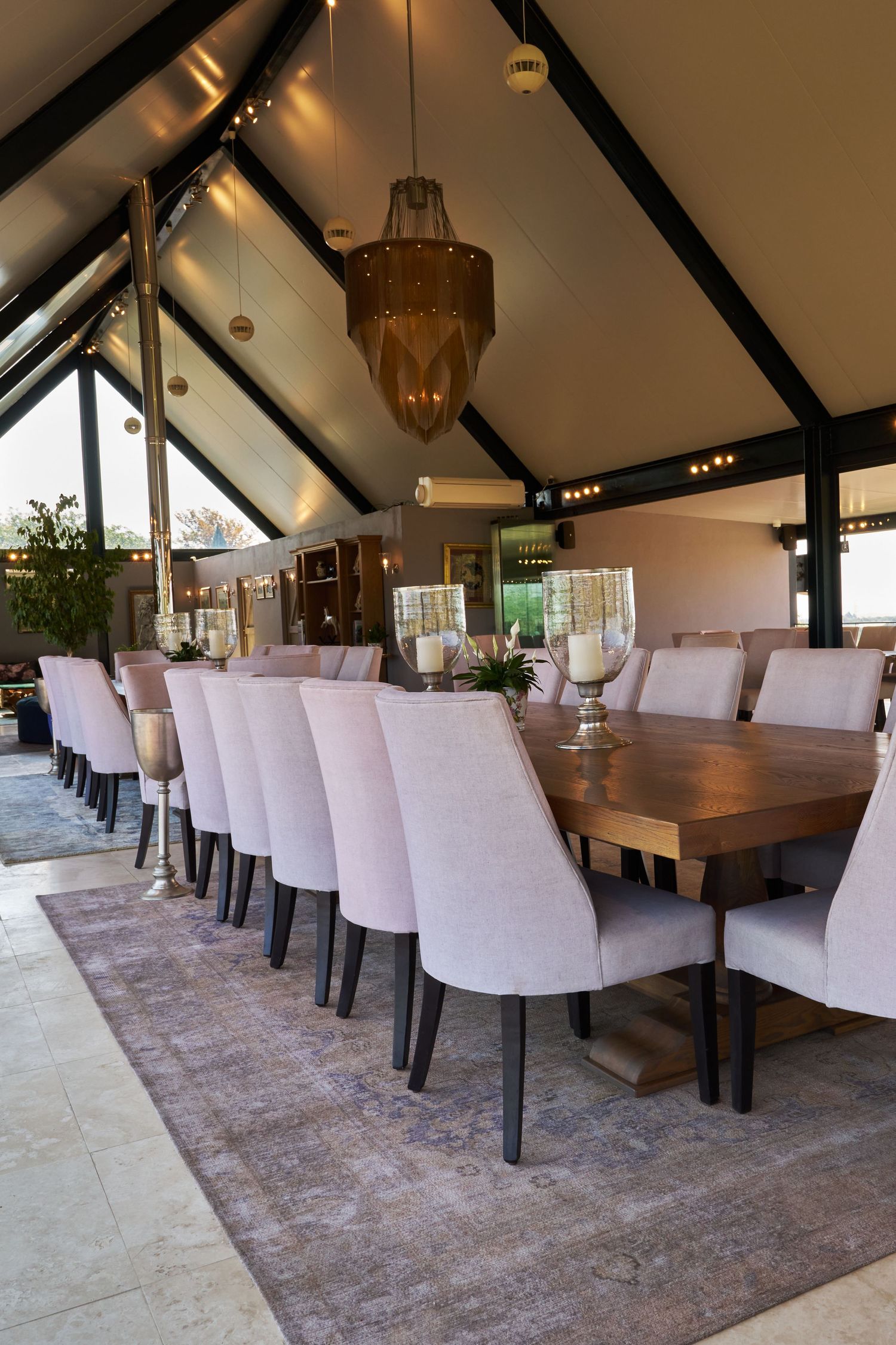 Grand dining room with long wooden table, upholstered chairs, vaulted ceiling, and elegant chandelier lighting.