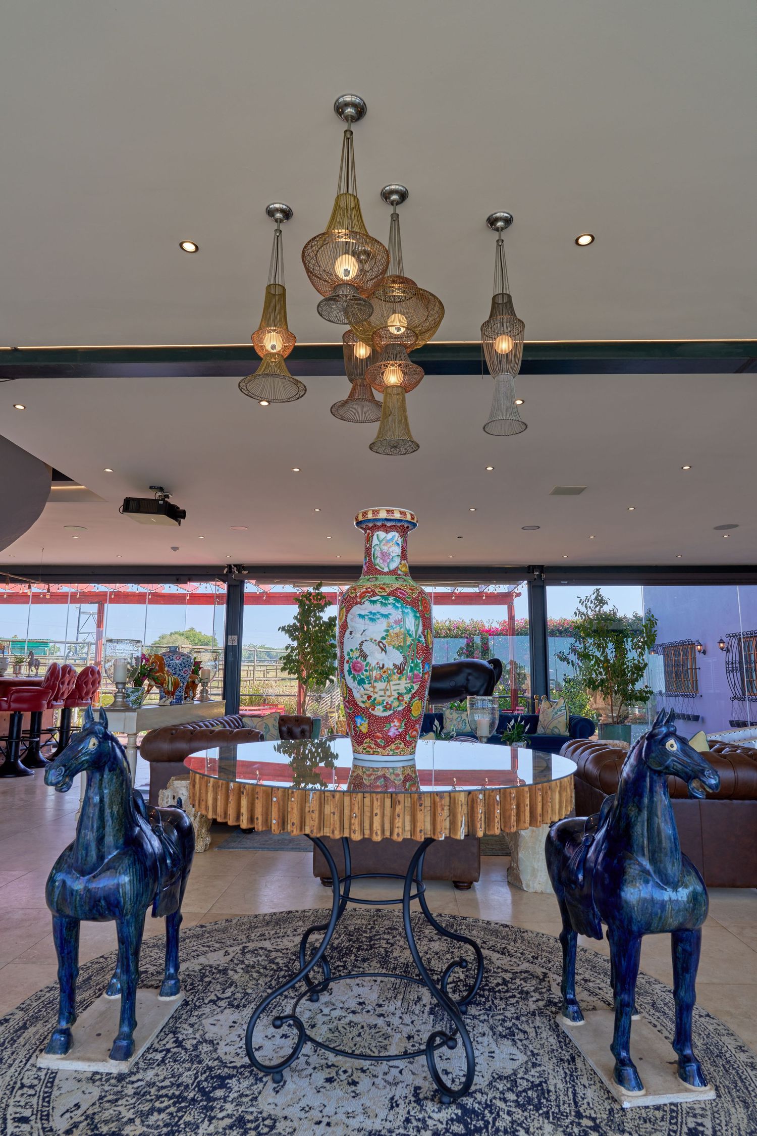 Luxury venue foyer with two blue horse statues, ornate vase centerpiece, and decorative pendant chandelier.