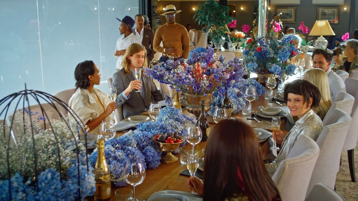 Guests enjoy an elaborate dinner party with stunning blue hydrangea floral centerpieces.