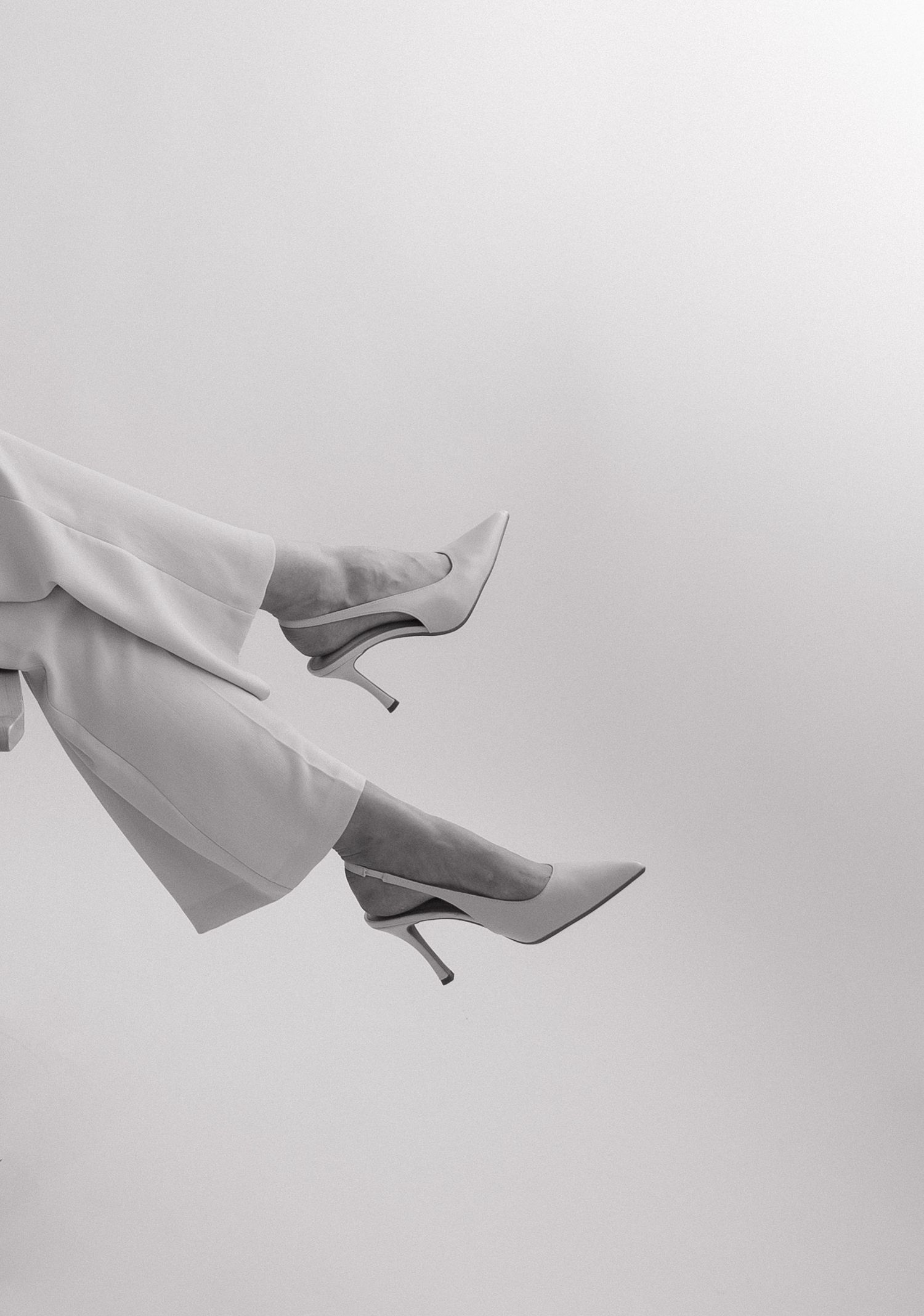 Black and white photo of womens legs wearing elegant stiletto heels and wide-leg trousers against a light background. Bundaberg photographer