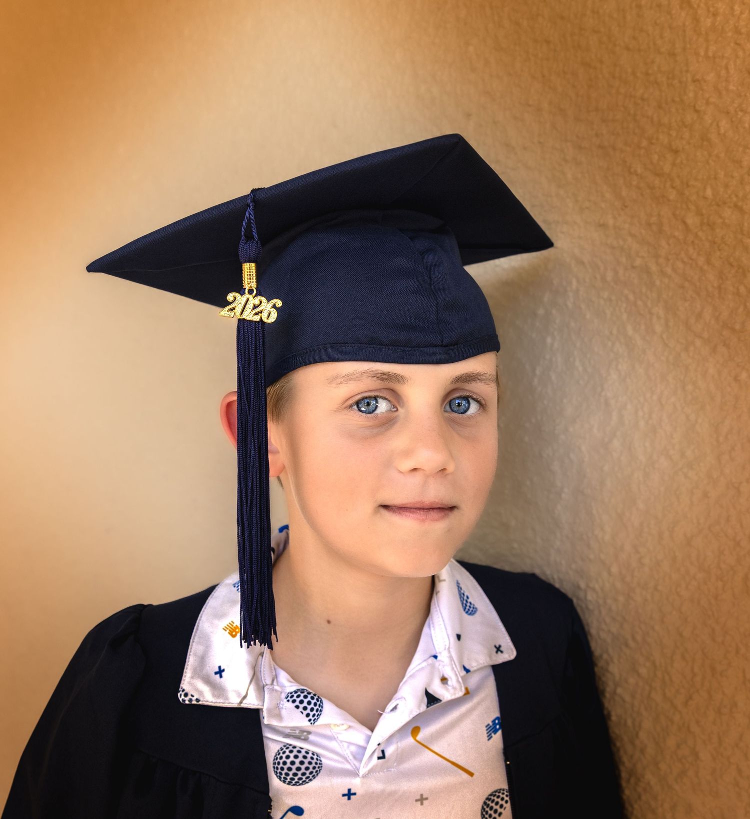 Young graduate wearing navy blue cap and gown with 2026 tassel, posing for graduation photo.