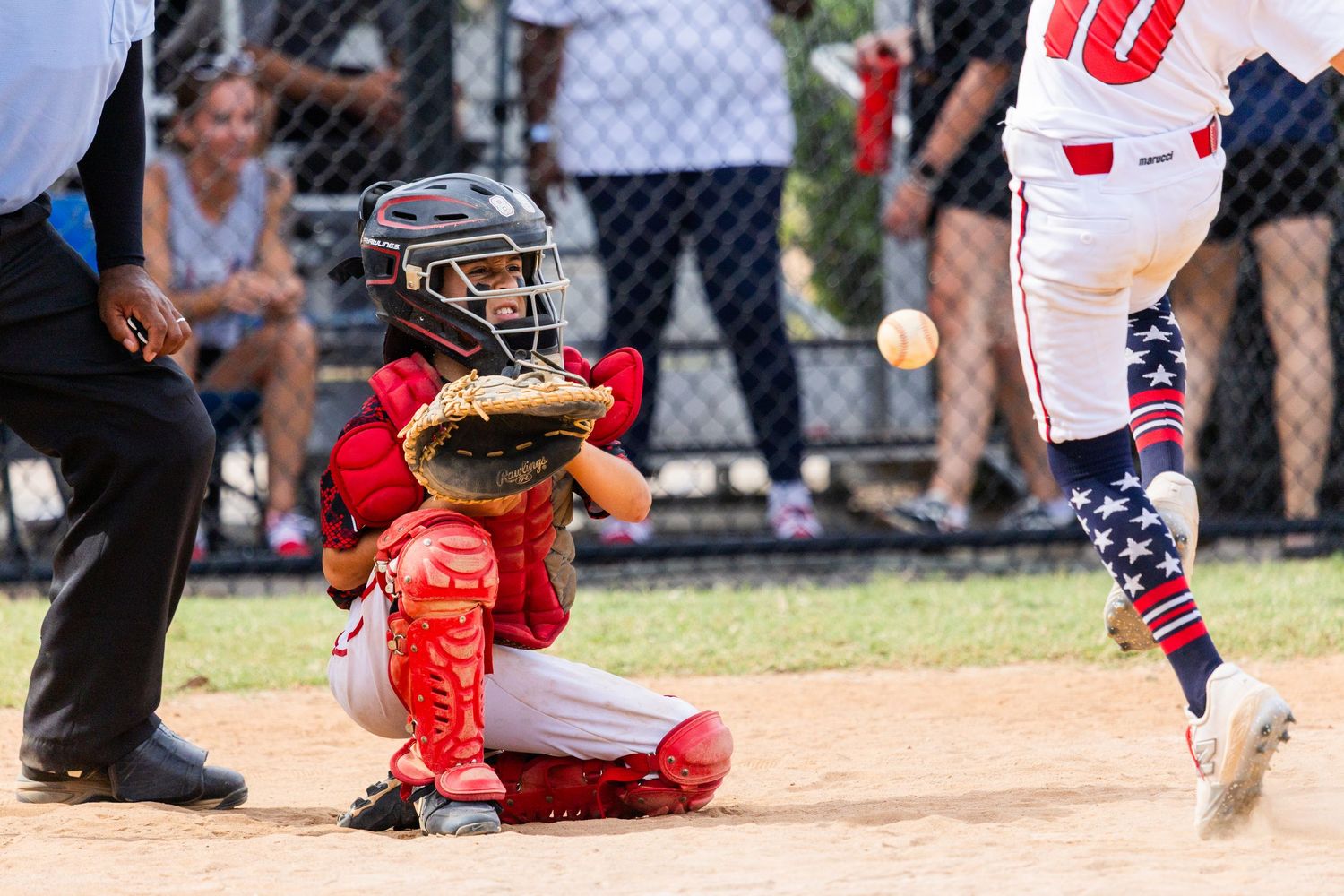 Baseball action shot showing players sliding and catching at home plate during game.