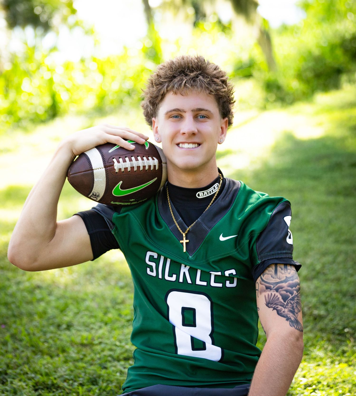 Young football player in Sickles #8 green jersey holding a football, smiling outdoors.