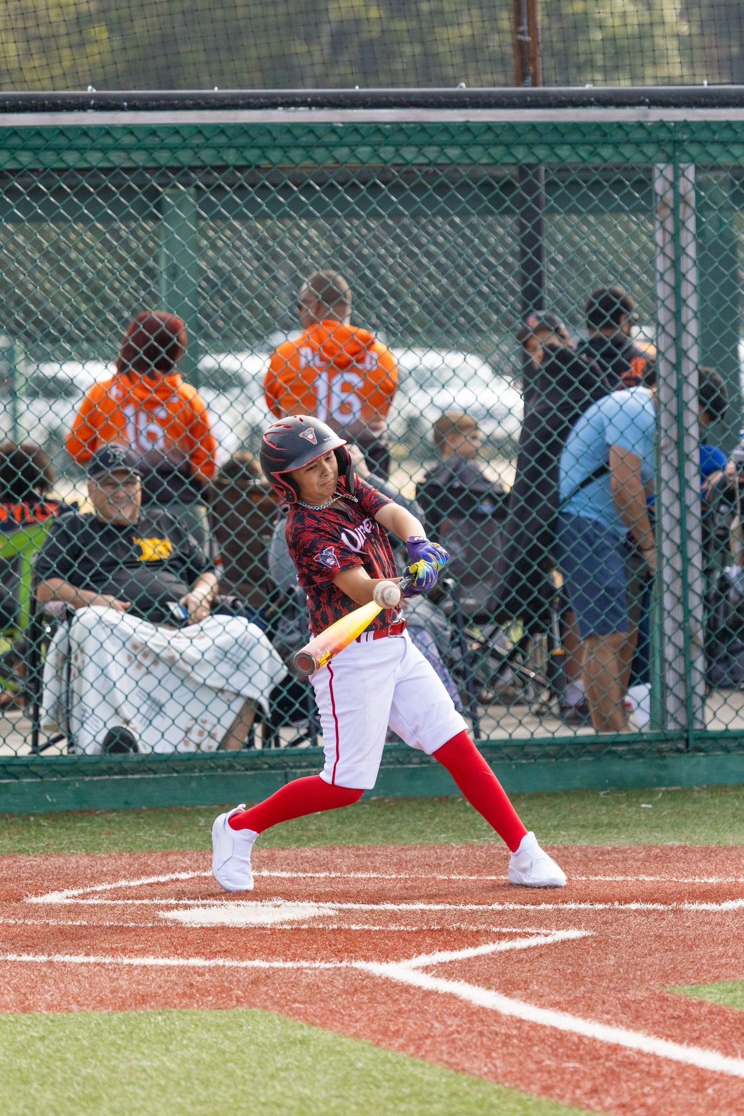 Baseball batter in red uniform swinging bat during game.