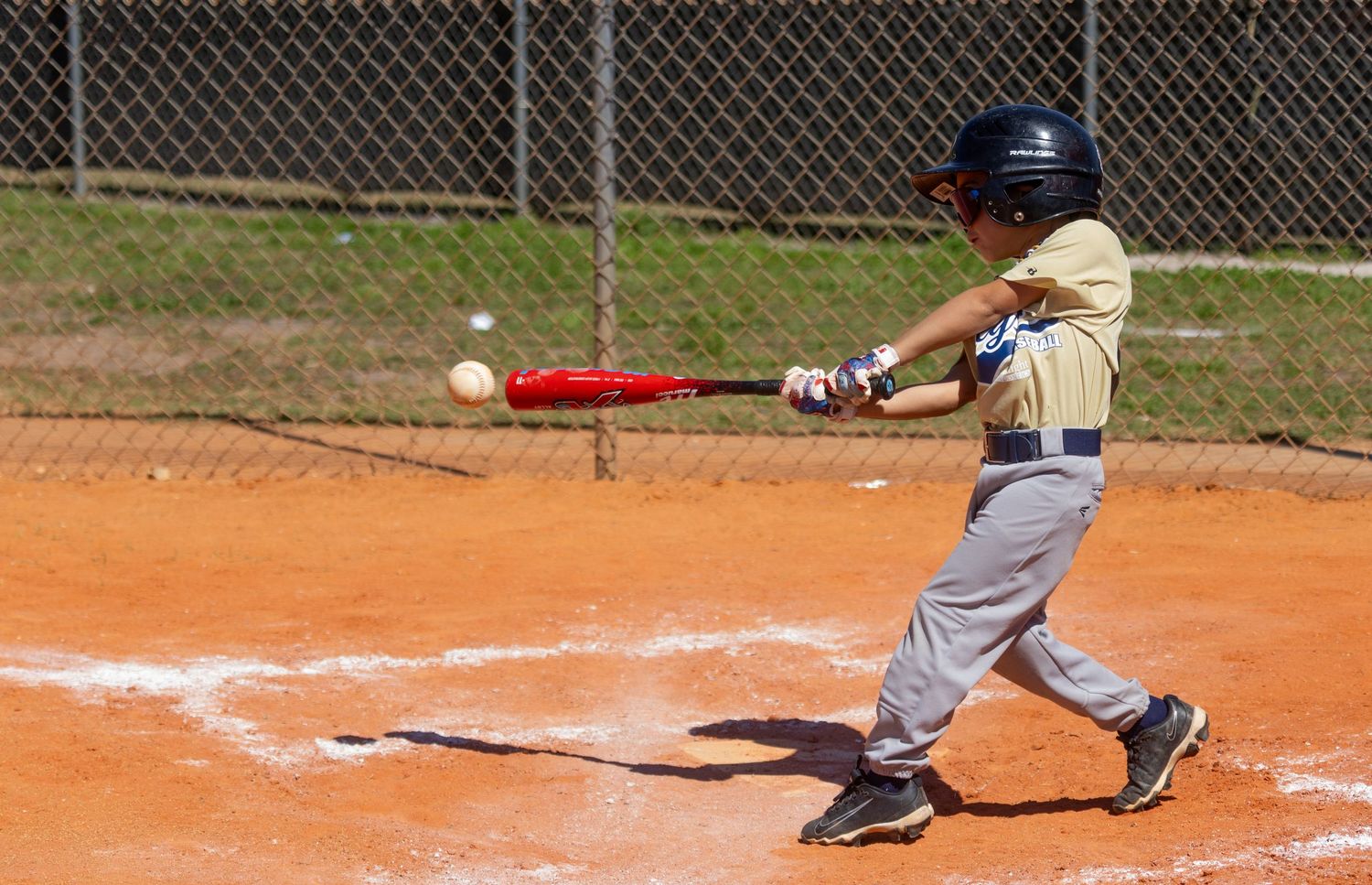 Baseball players in various batting positions during a youth league game on a dirt field.