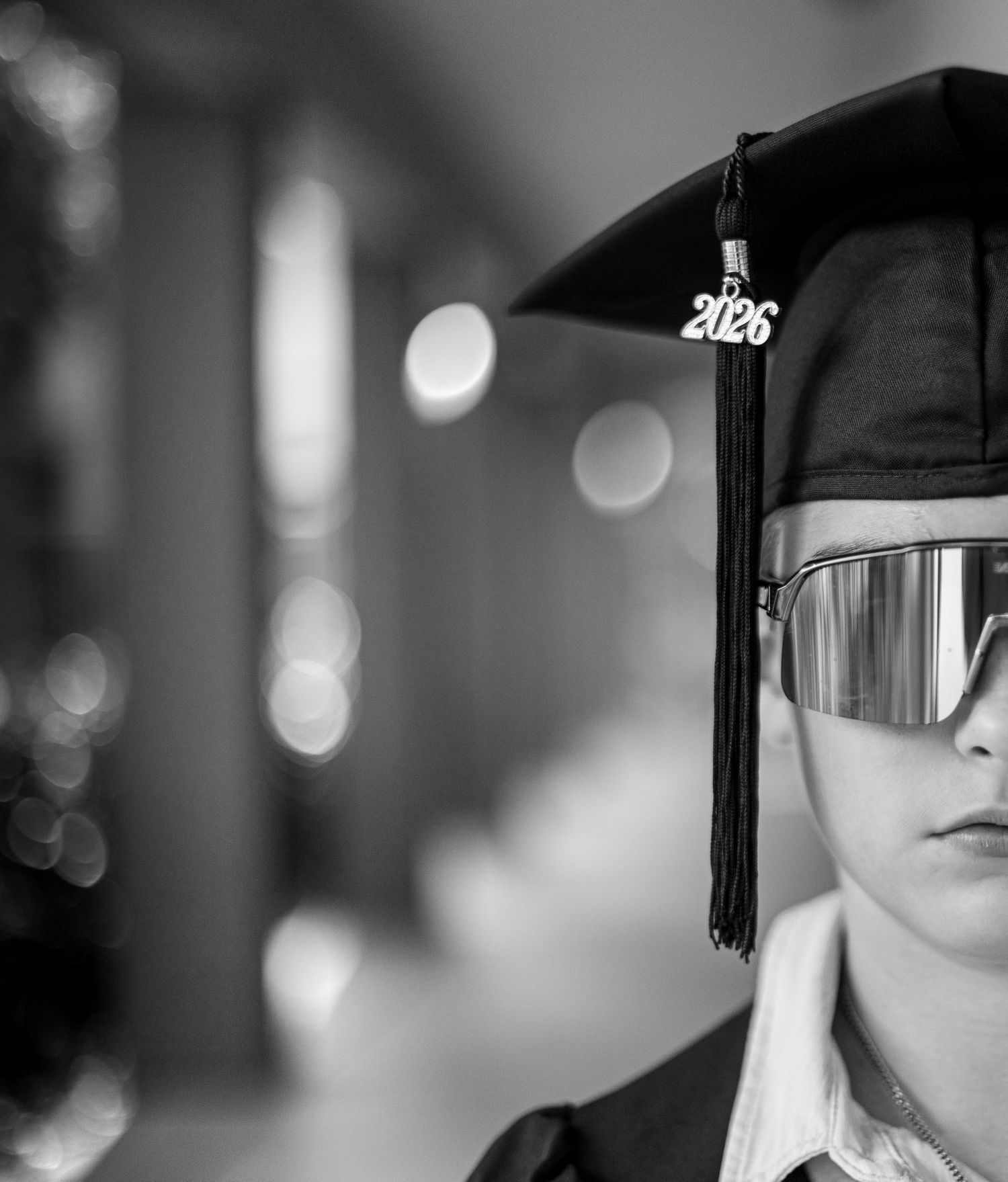Black and white photo of a student in graduation cap with 2026 tassel and reflective sunglasses.