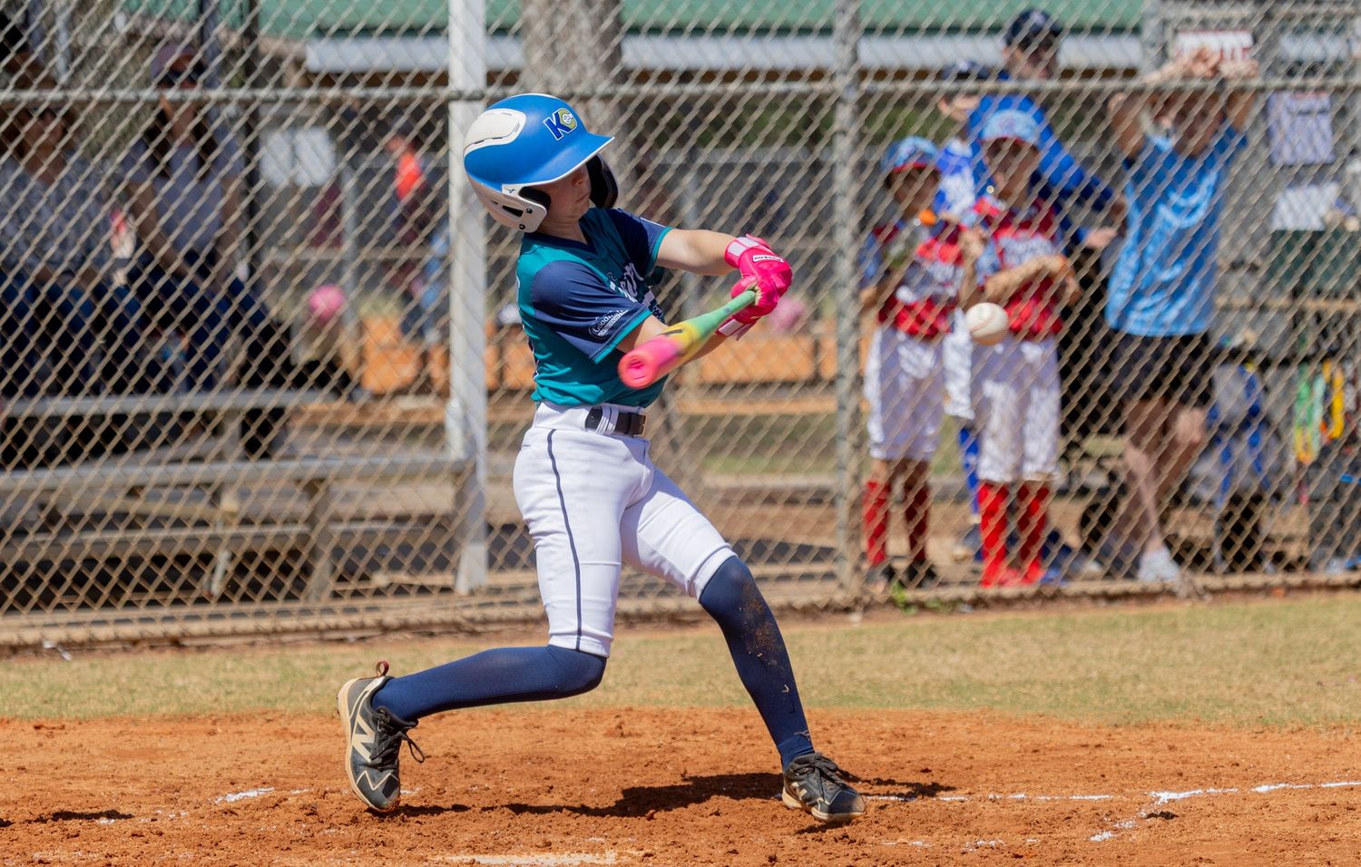 Baseball players in various batting positions during a youth league game on a dirt field.