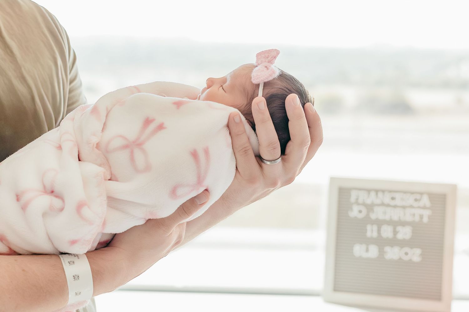 Newborn baby Francesca Jo Jonnett wrapped in pink blanket being held by parent in hospital room.