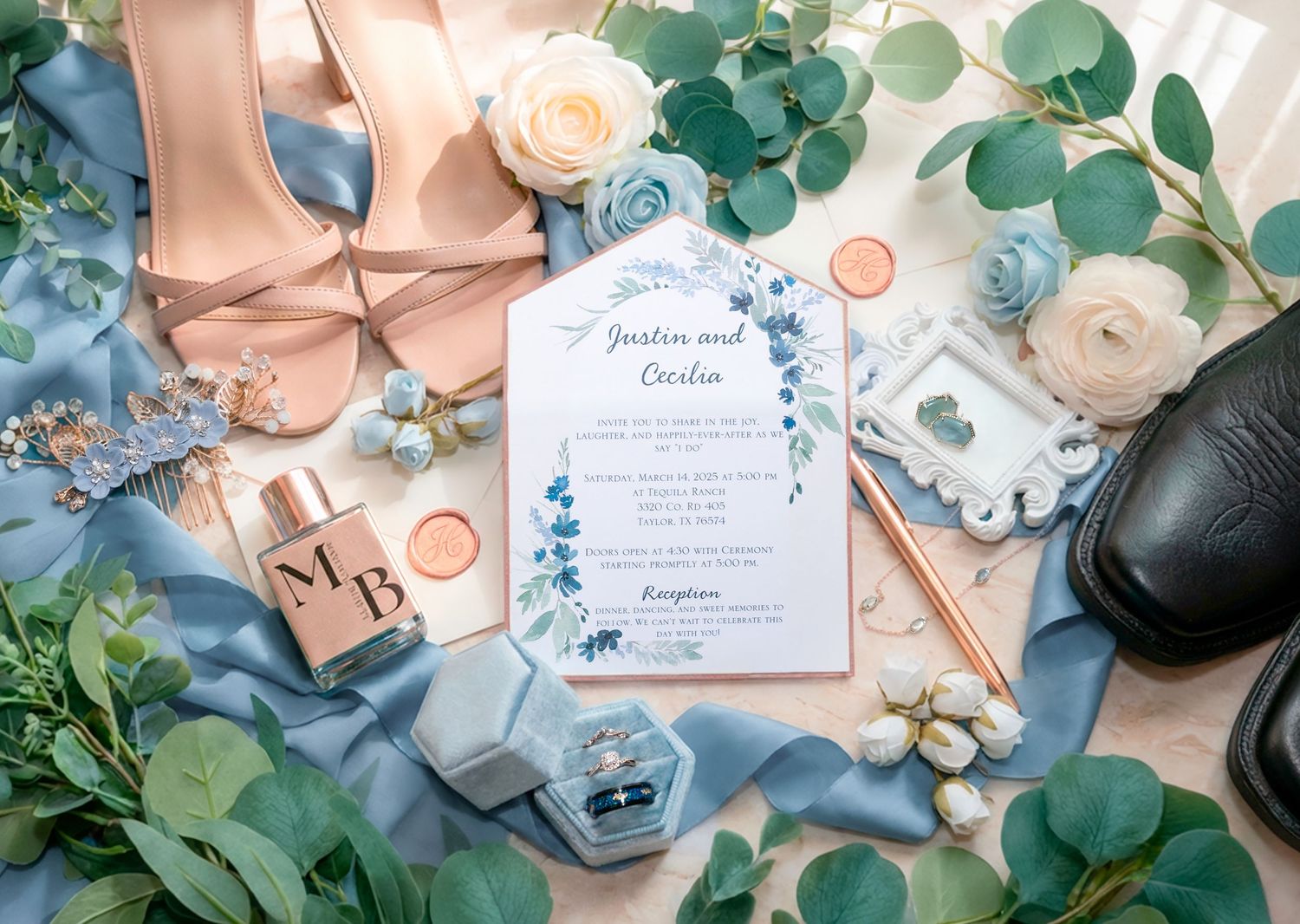 Wedding flat lay with dusty blue floral invitation, blush heels, mens shoes, rings, and fresh eucalyptus.