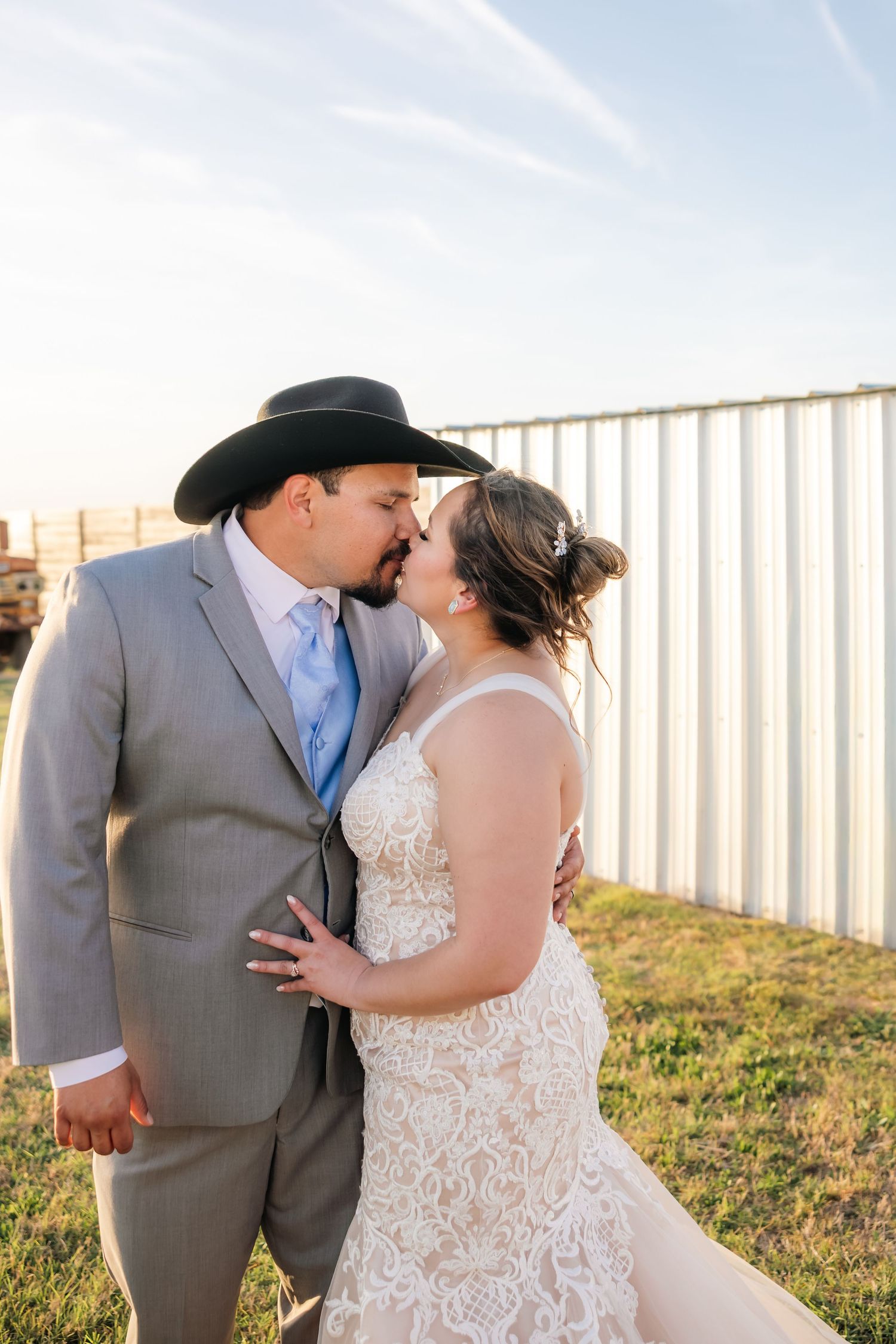 A bride and groom share a romantic moment at sunset during their country western wedding.