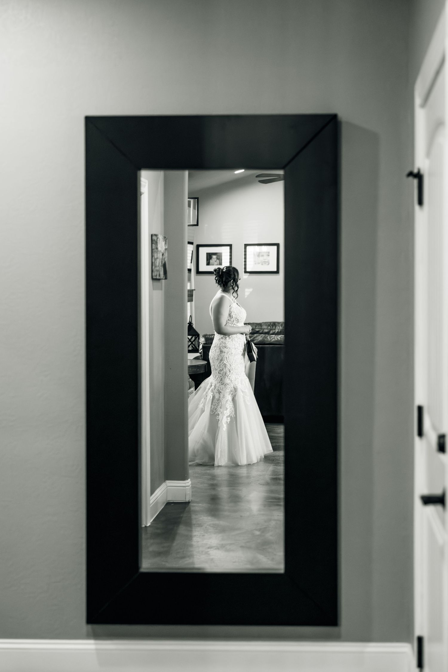 Black and white mirror reflection of a bride in a lace mermaid wedding gown getting ready.