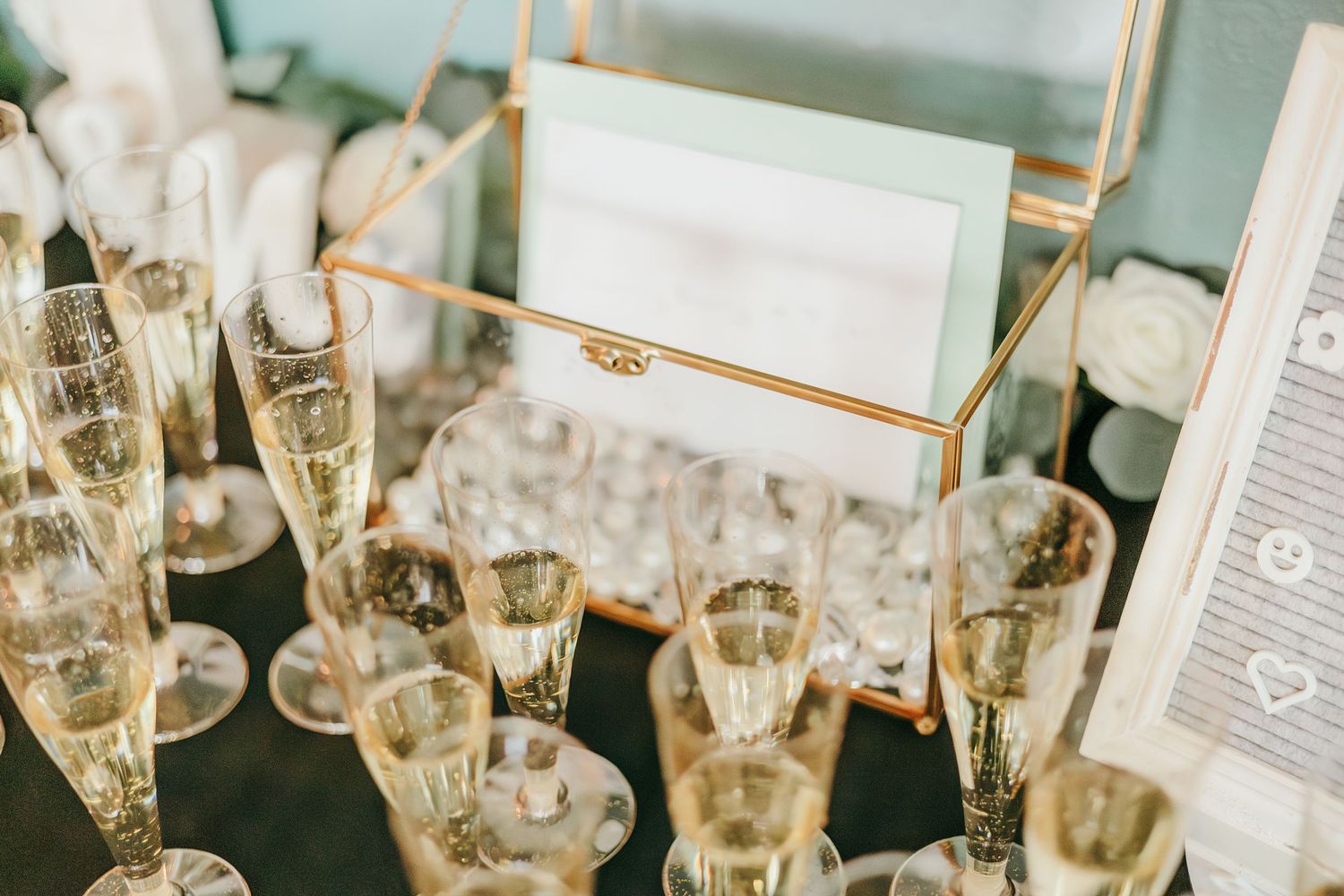 Elegant champagne flutes filled with sparkling wine displayed on a gold geometric frame at wedding.