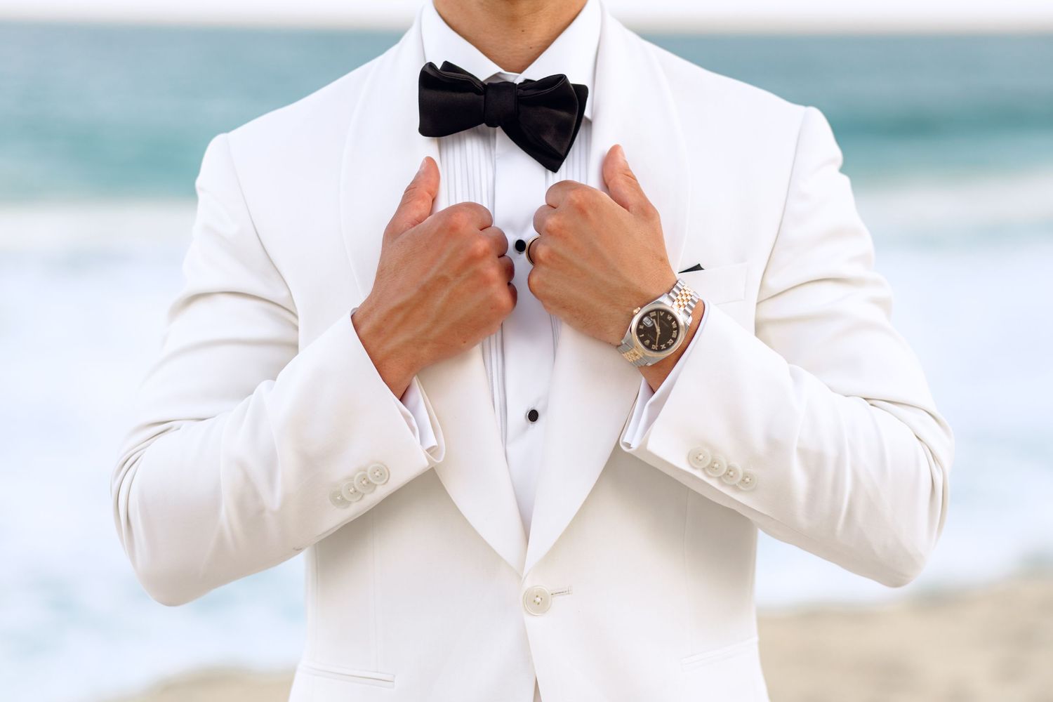 Close-up of a white tuxedo jacket with black bow tie against an ocean backdrop.