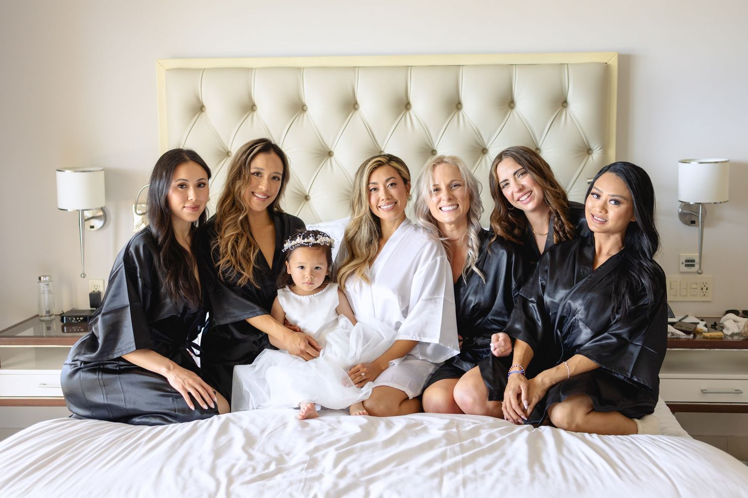 Group relaxing together on a white bed with matching black robes.