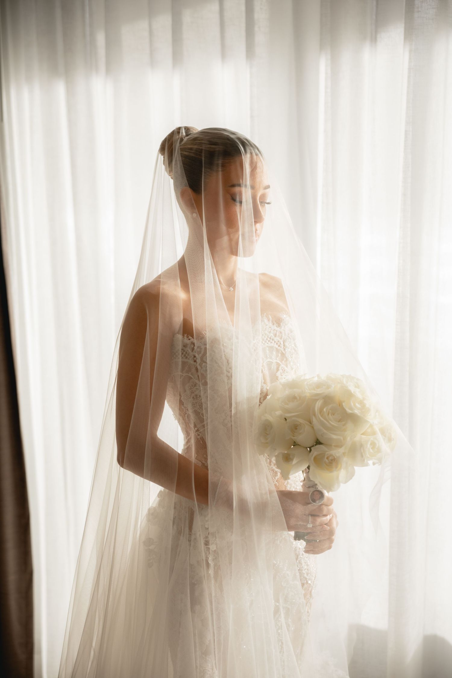 Artistic bridal portrait through sheer veil with white bouquet.