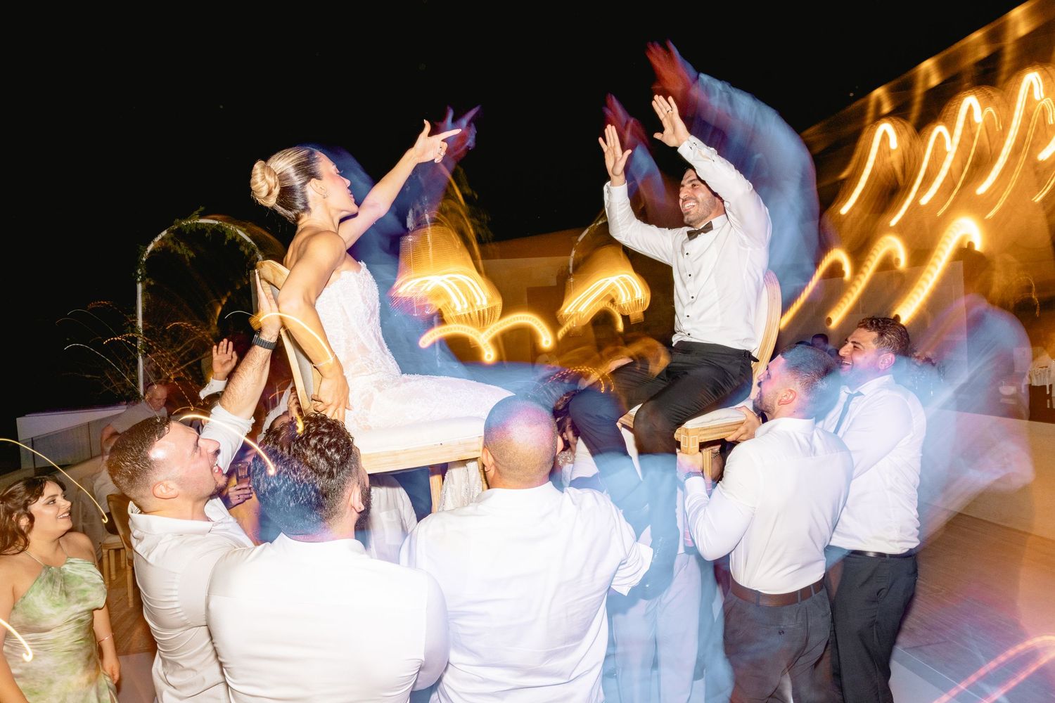 Wedding reception dance party with guests celebrating under ambient lighting.