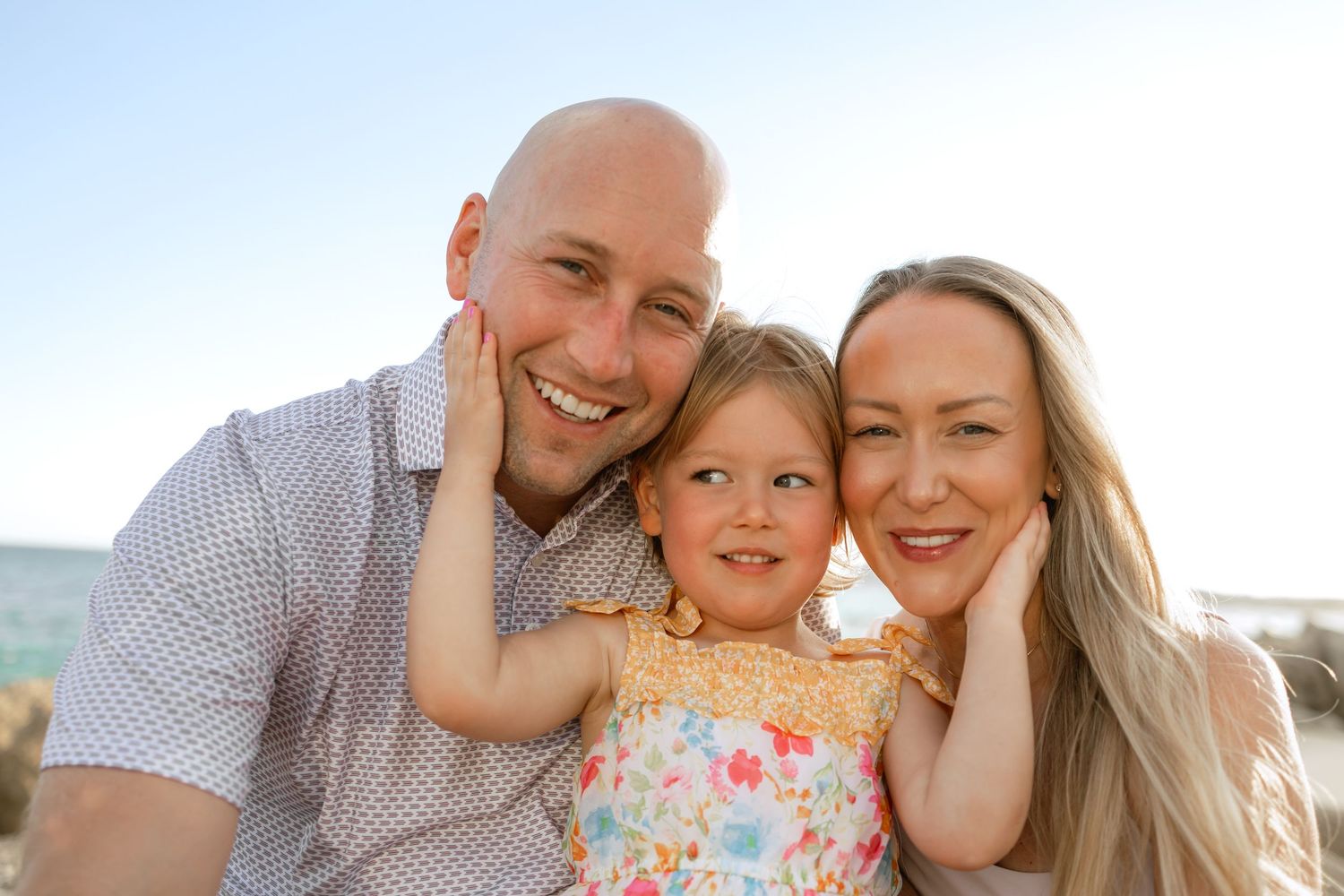 Family enjoying a playful moment together outdoors during a sunset photo session at the beach at Garza Blanca, Los Cabos