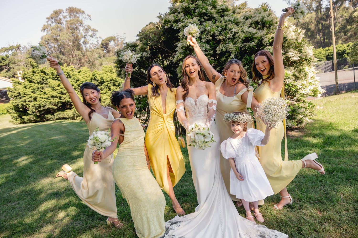 Wedding party celebrating outdoors with yellow dresses and white gowns.