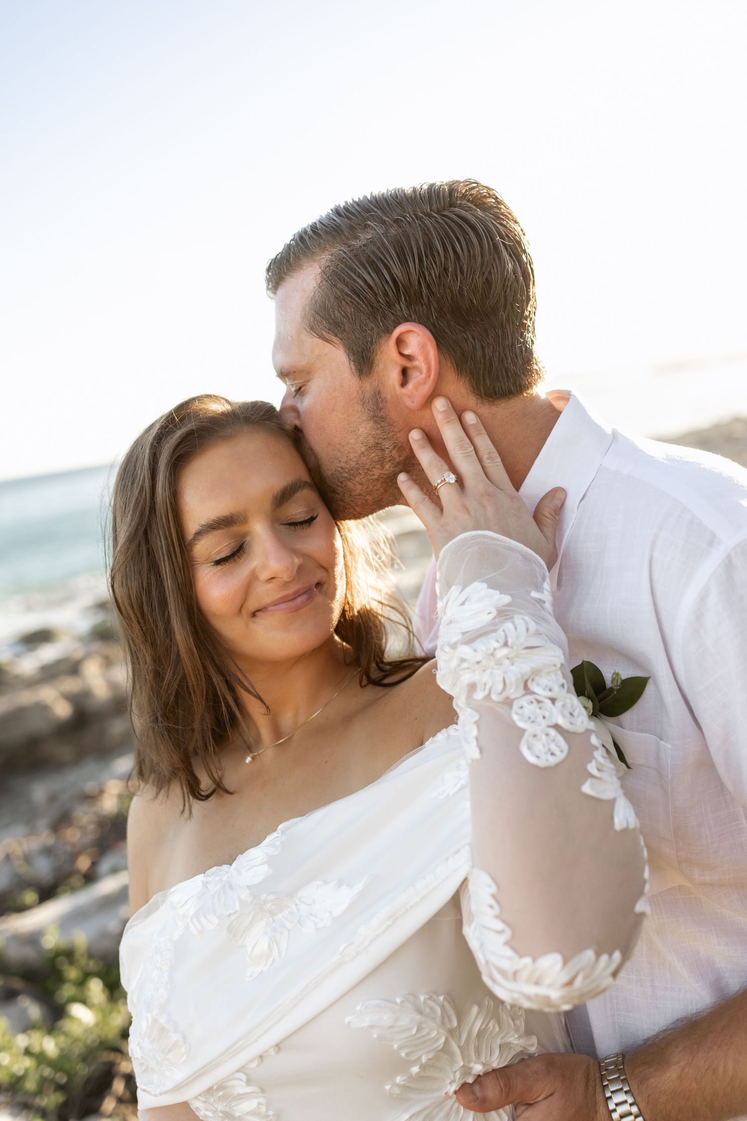 Intimate beach portrait session with couple in white clothing during golden hour.