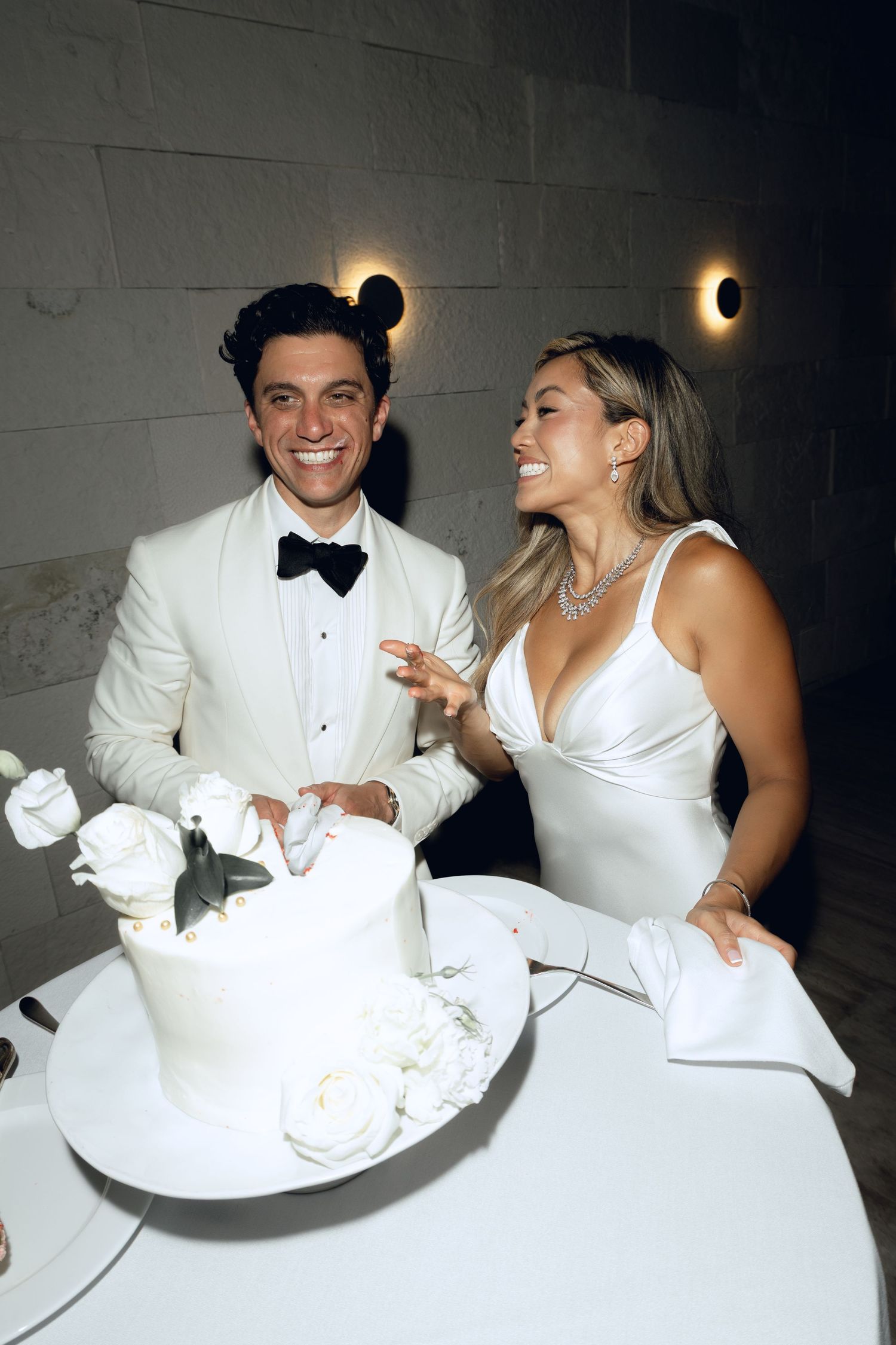 Bride and groom sharing a lighthearted cake-smashing moment at their wedding reception.