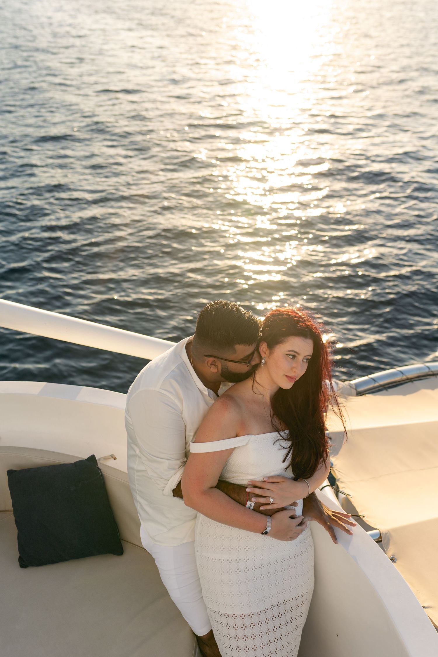 A romantic sunset moment aboard a boat on calm waters with golden light reflecting off the ocean surface.