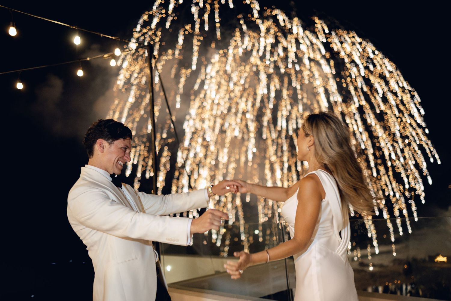 Fireworks light up the night sky during a romantic beach wedding celebration.