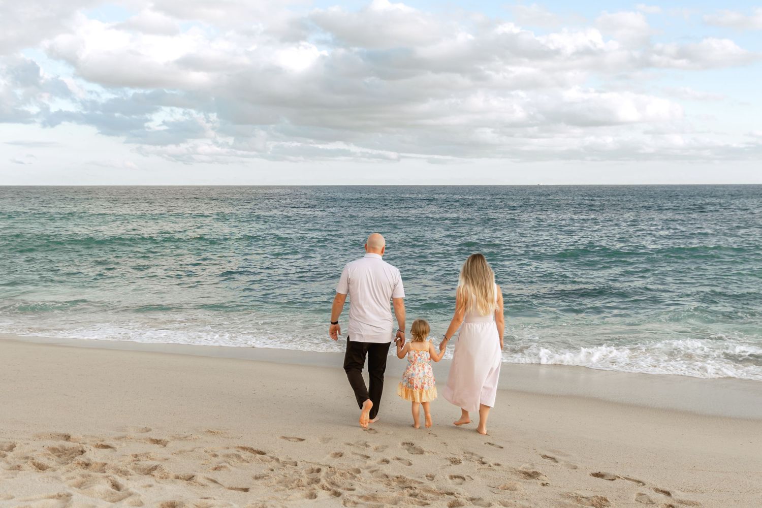 People strolling along a peaceful beach with waves rolling in.