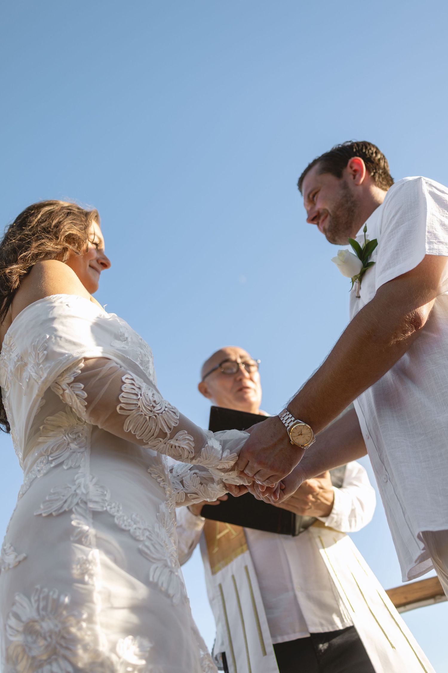 Close-up of hands exchanging wedding rings during an outdoor ceremony.