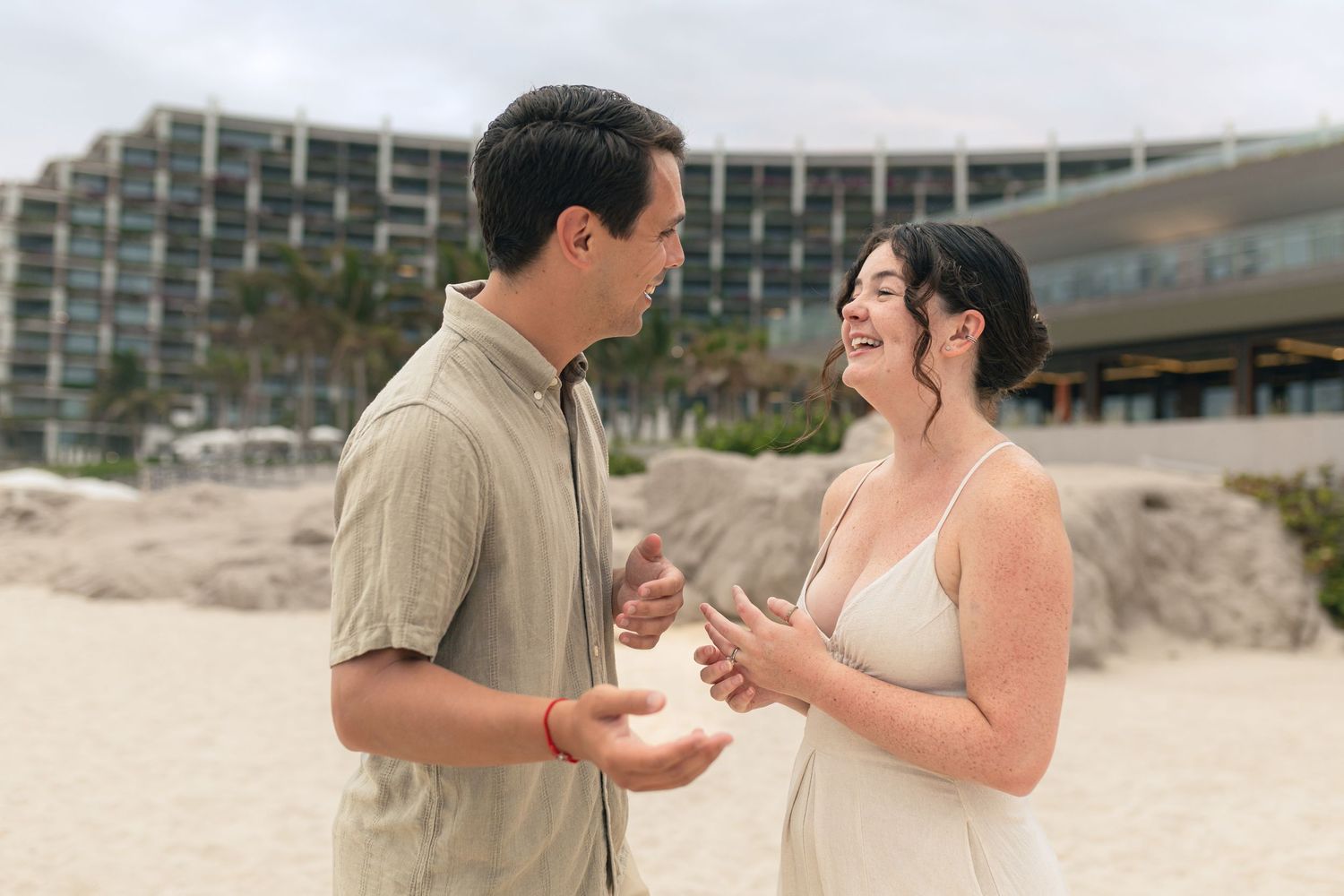 A couple exchanges rings during a beach wedding ceremony at sunset.