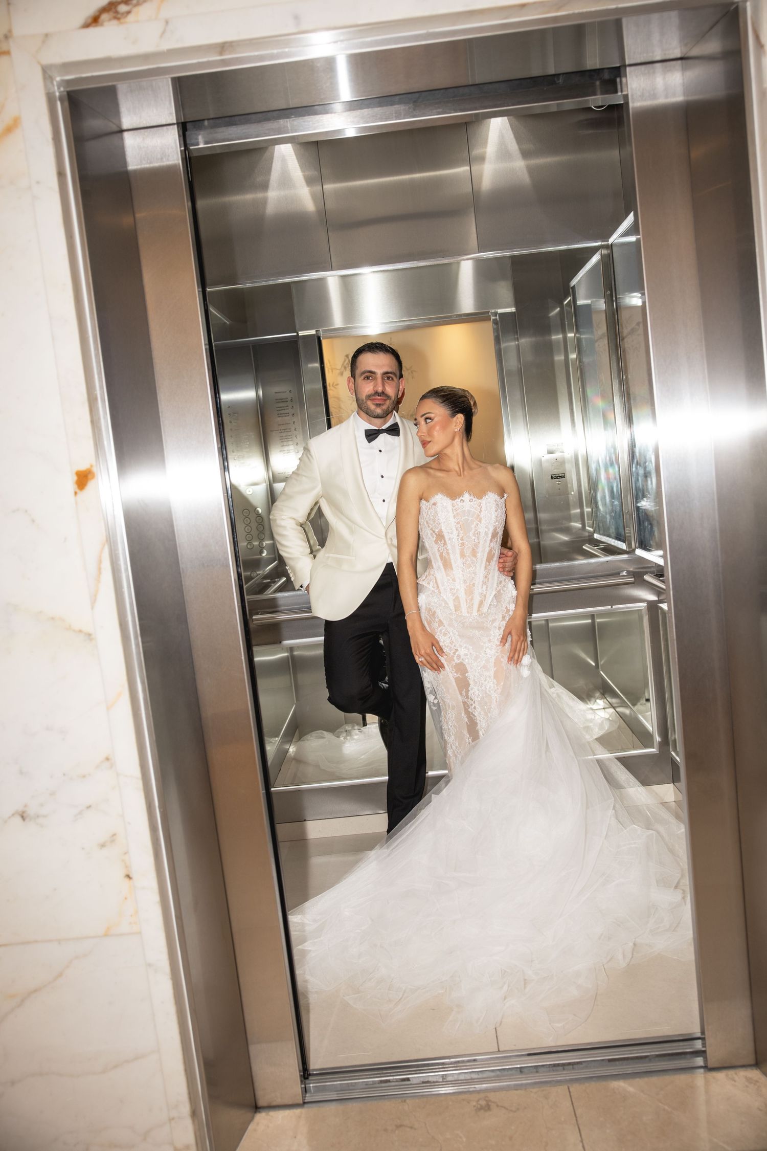 Wedding couple sharing playful moments in a modern elevator.