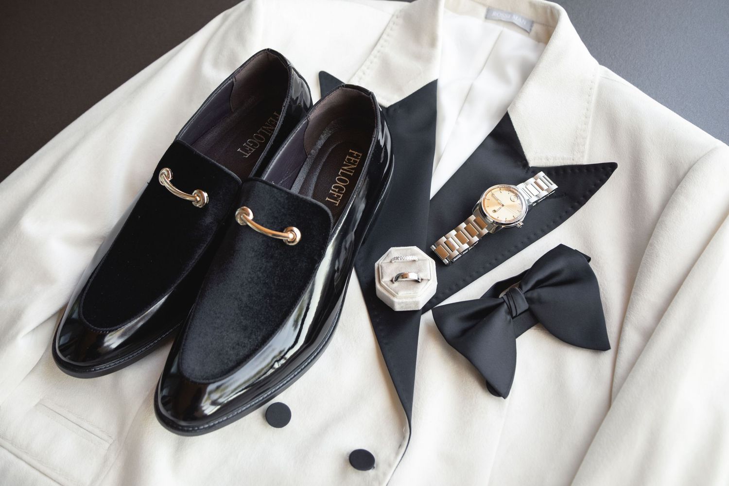 Formal black dress shoes and bow ties laid out with white wedding attire.
