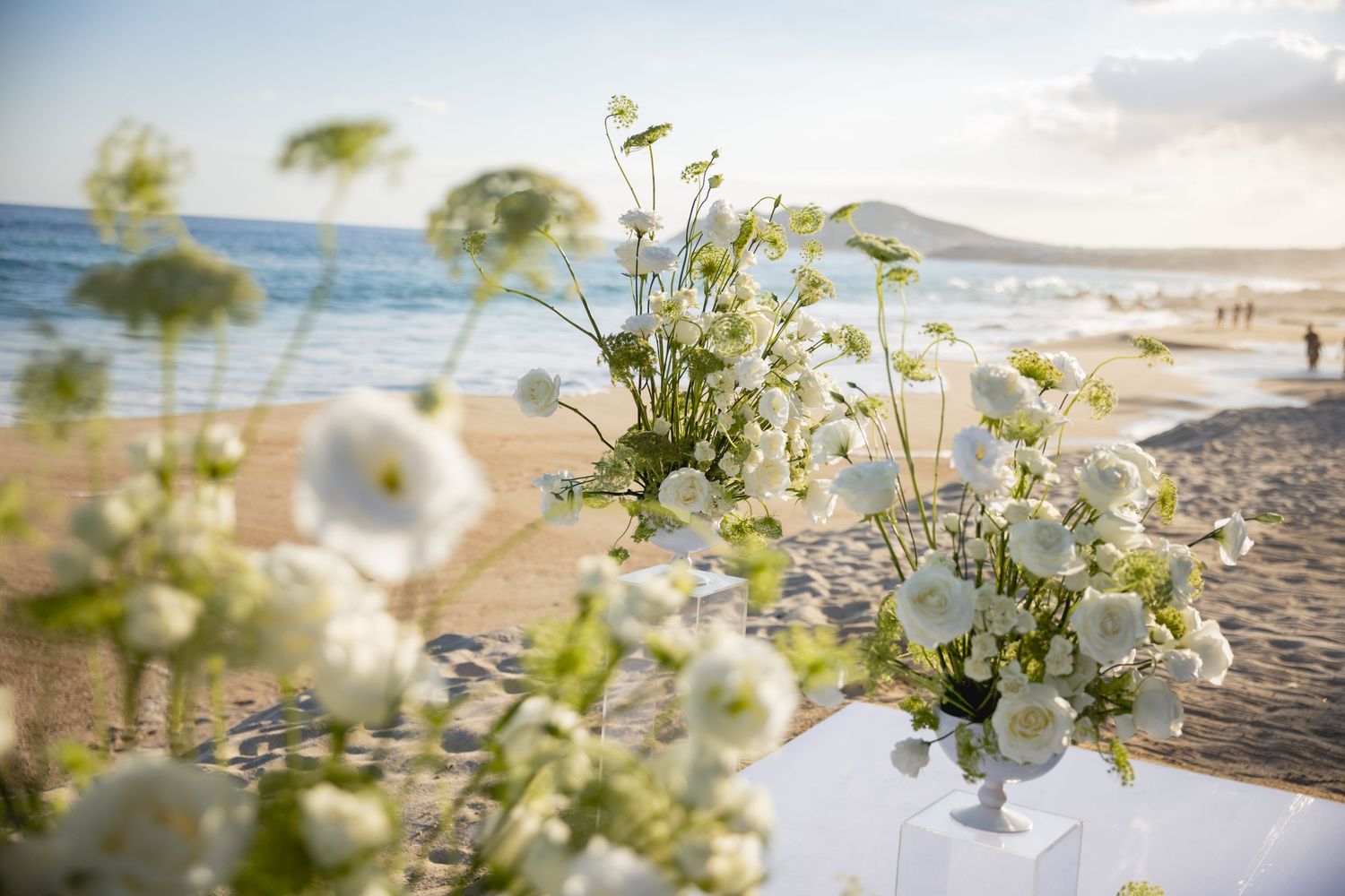 Delicate white floral arrangements with ocean view in the background.