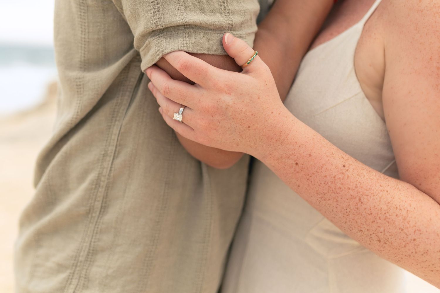 Close-up of engaged couple's hands showing diamond ring during outdoor engagement photo session.
